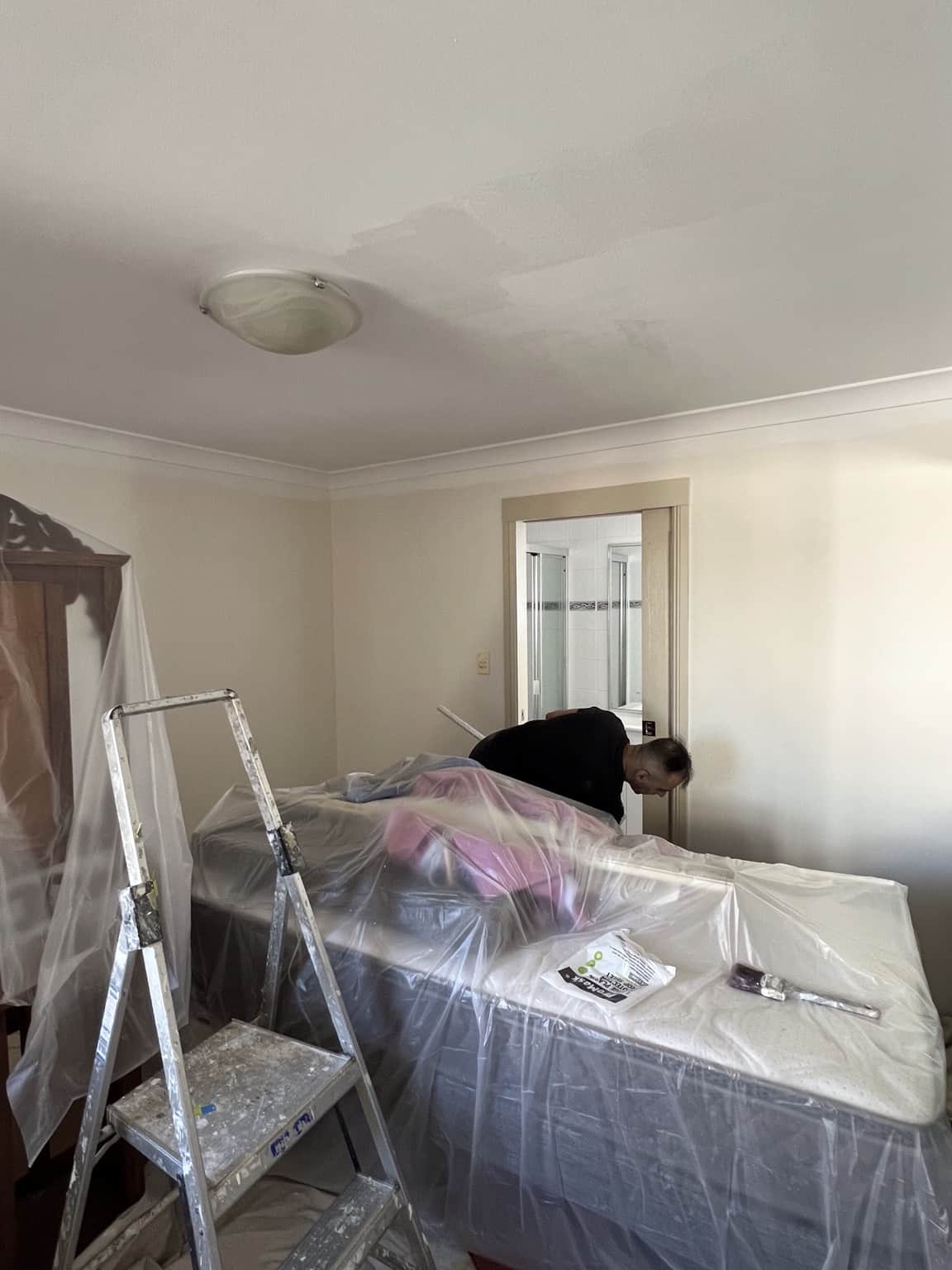 Bedroom furniture protected during preparation for interior painting in Merrylands