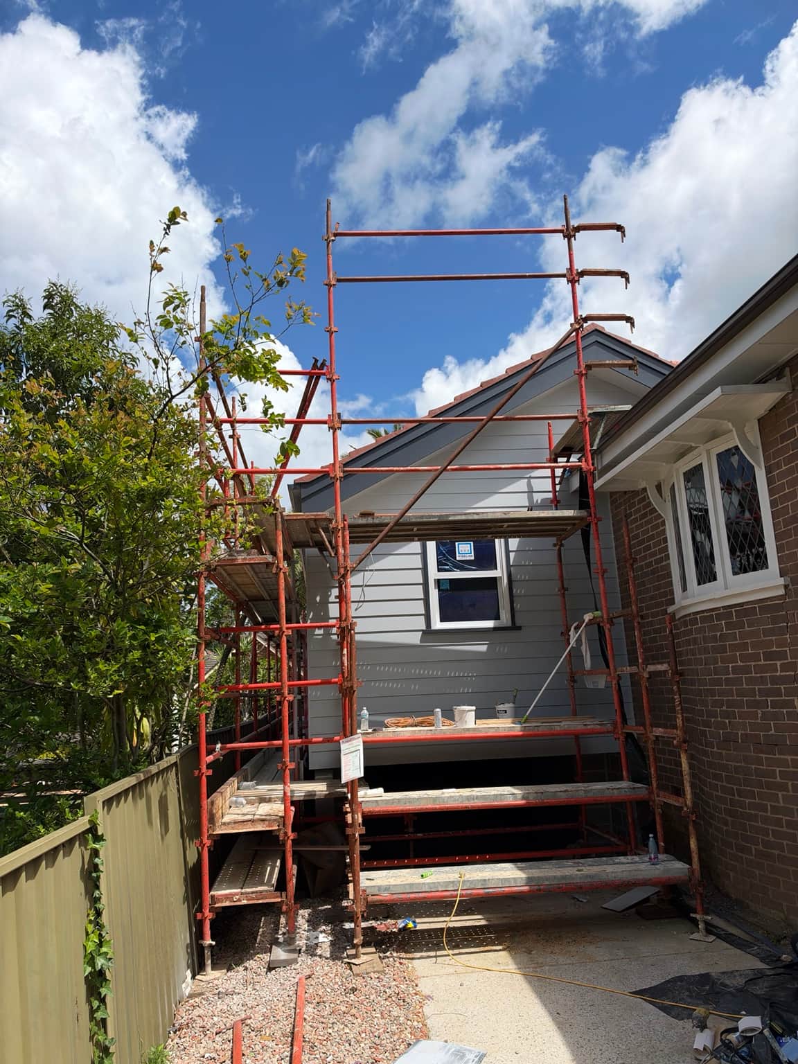 Painted gable and light weatherboard cladding beside existing brickwork at the Beecroft property