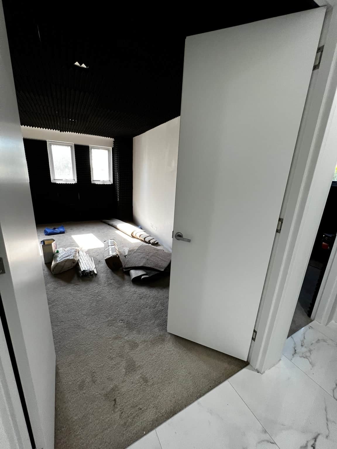 Painted white door and wall beside black acoustic panels in a music room