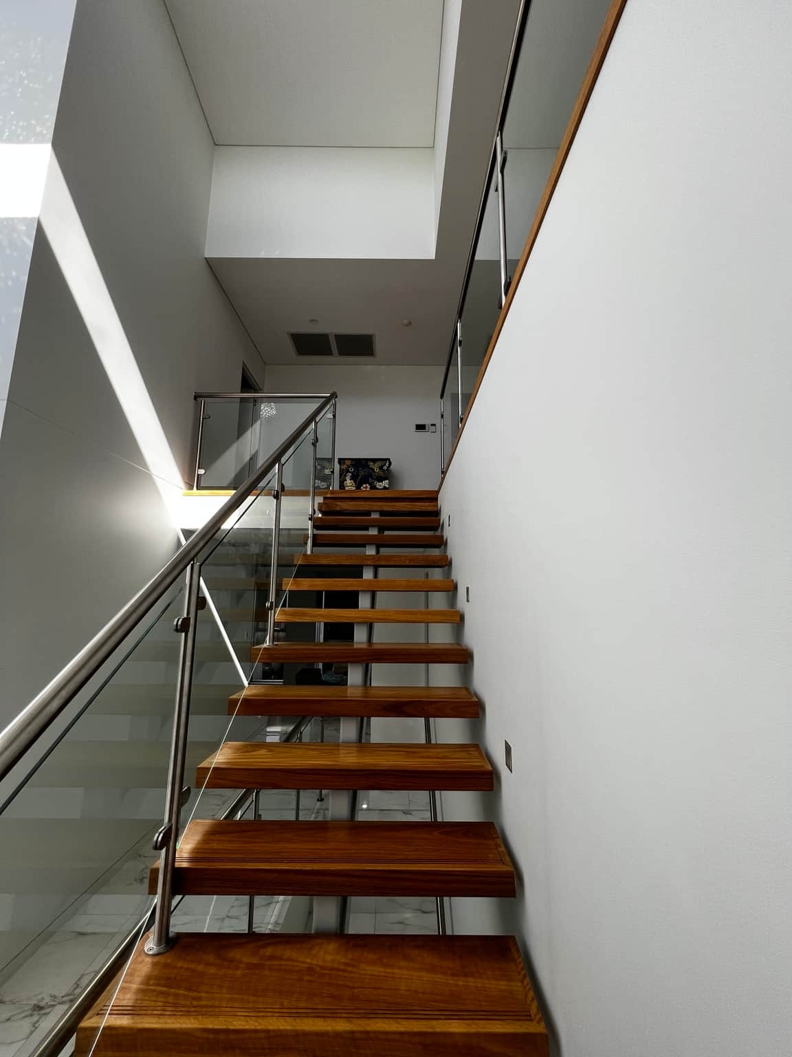Painted stairwell walls above timber stairs and glass balustrades