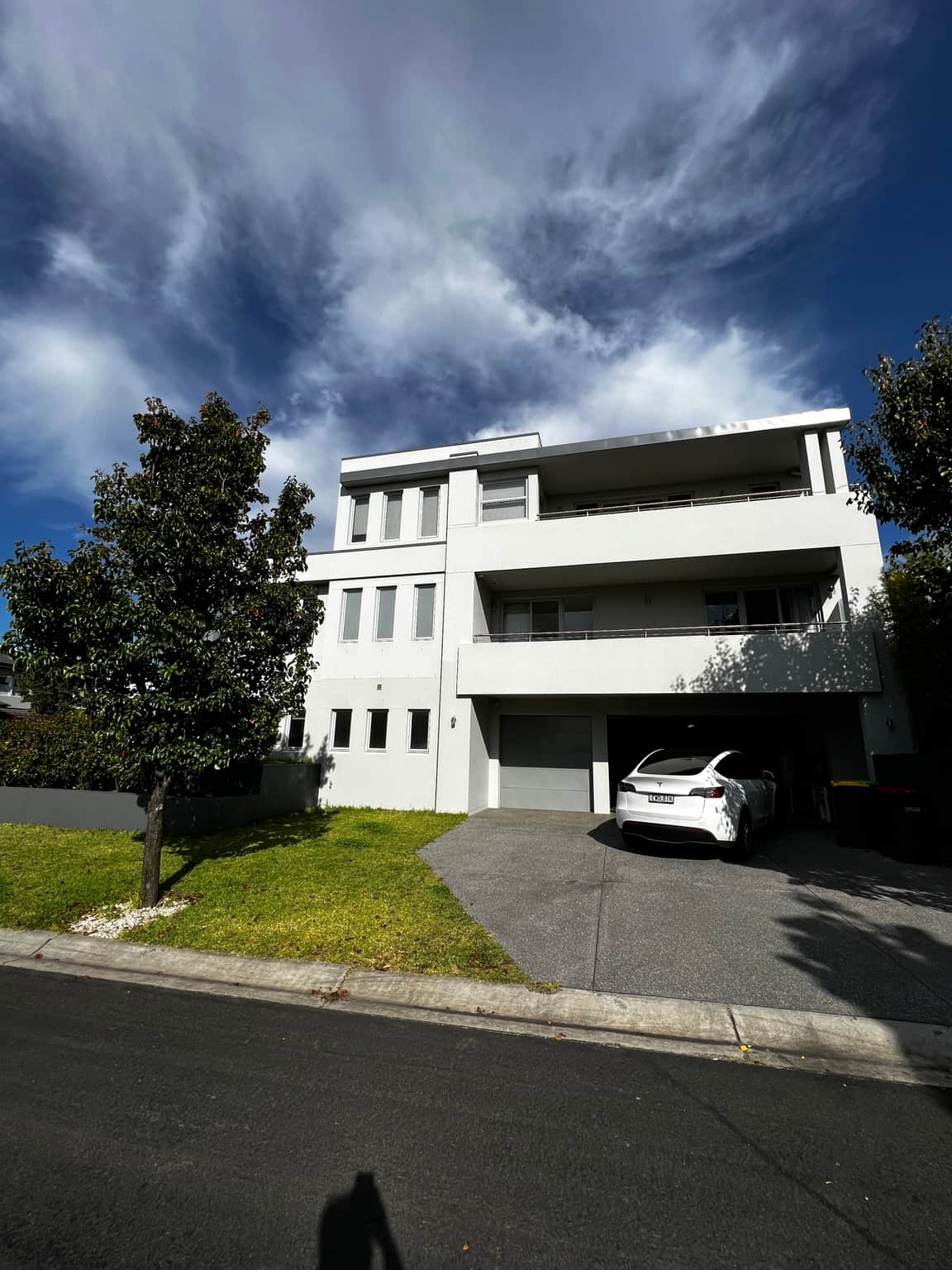 Multi-storey Bella Vista home with white exterior walls, recessed balconies and grey fascia
