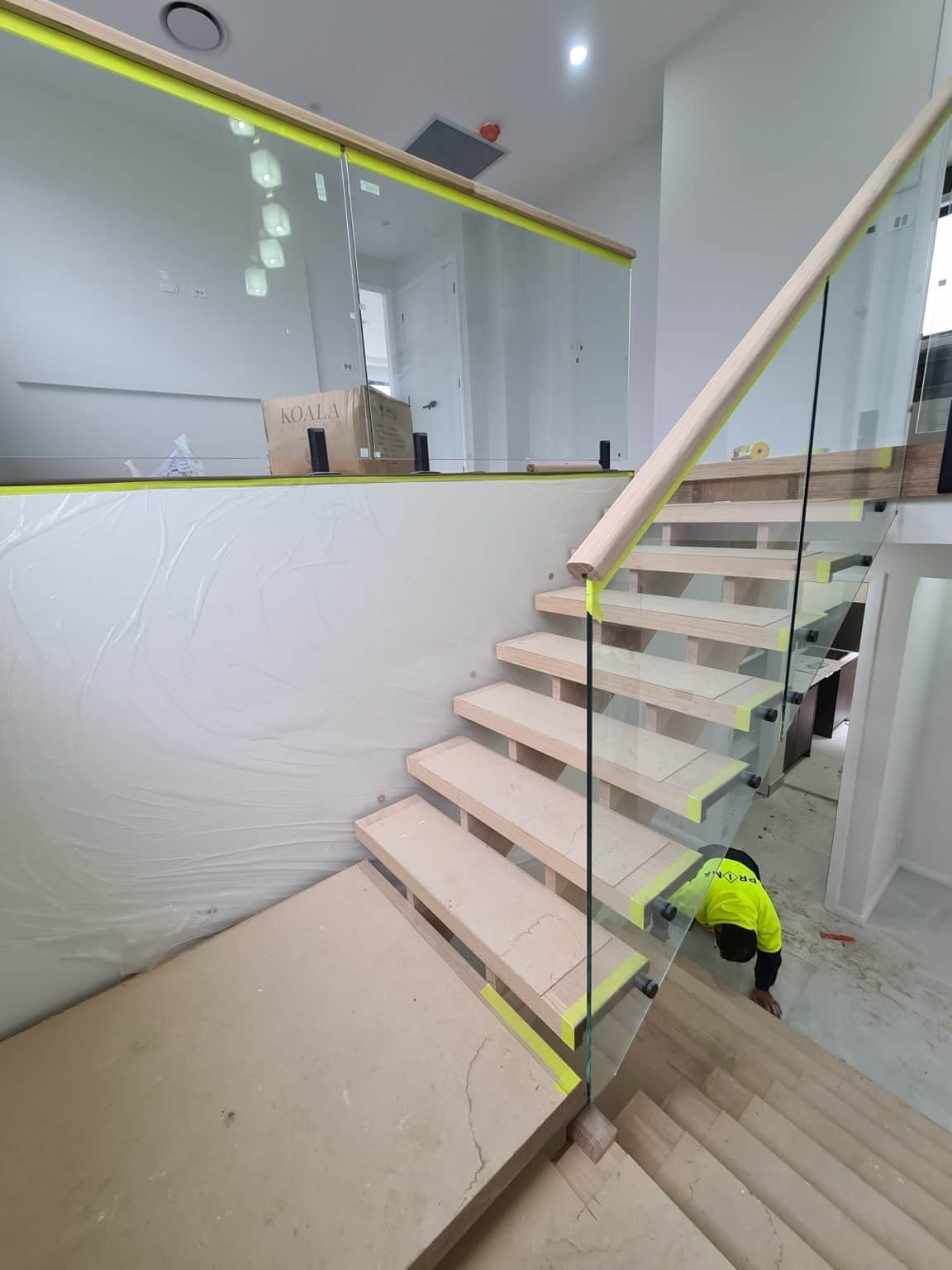 Box Hill timber staircase before staining, showing bare treads, handrail and protective masking.