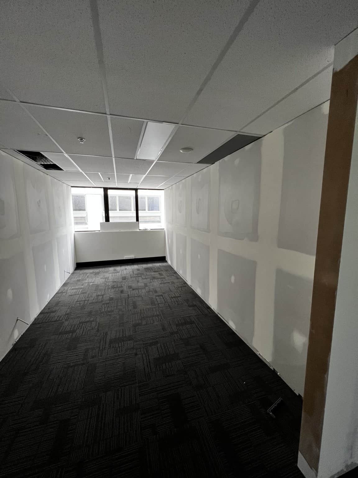 Small Chatswood office with plastered wall joints, suspended ceiling and an end window.