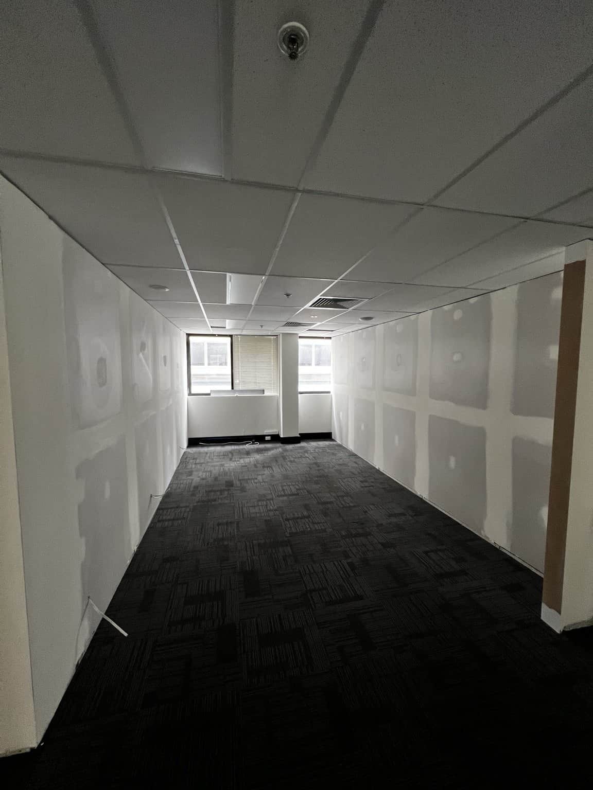View through a Chatswood office room with filled wall joints and a window at the far end.