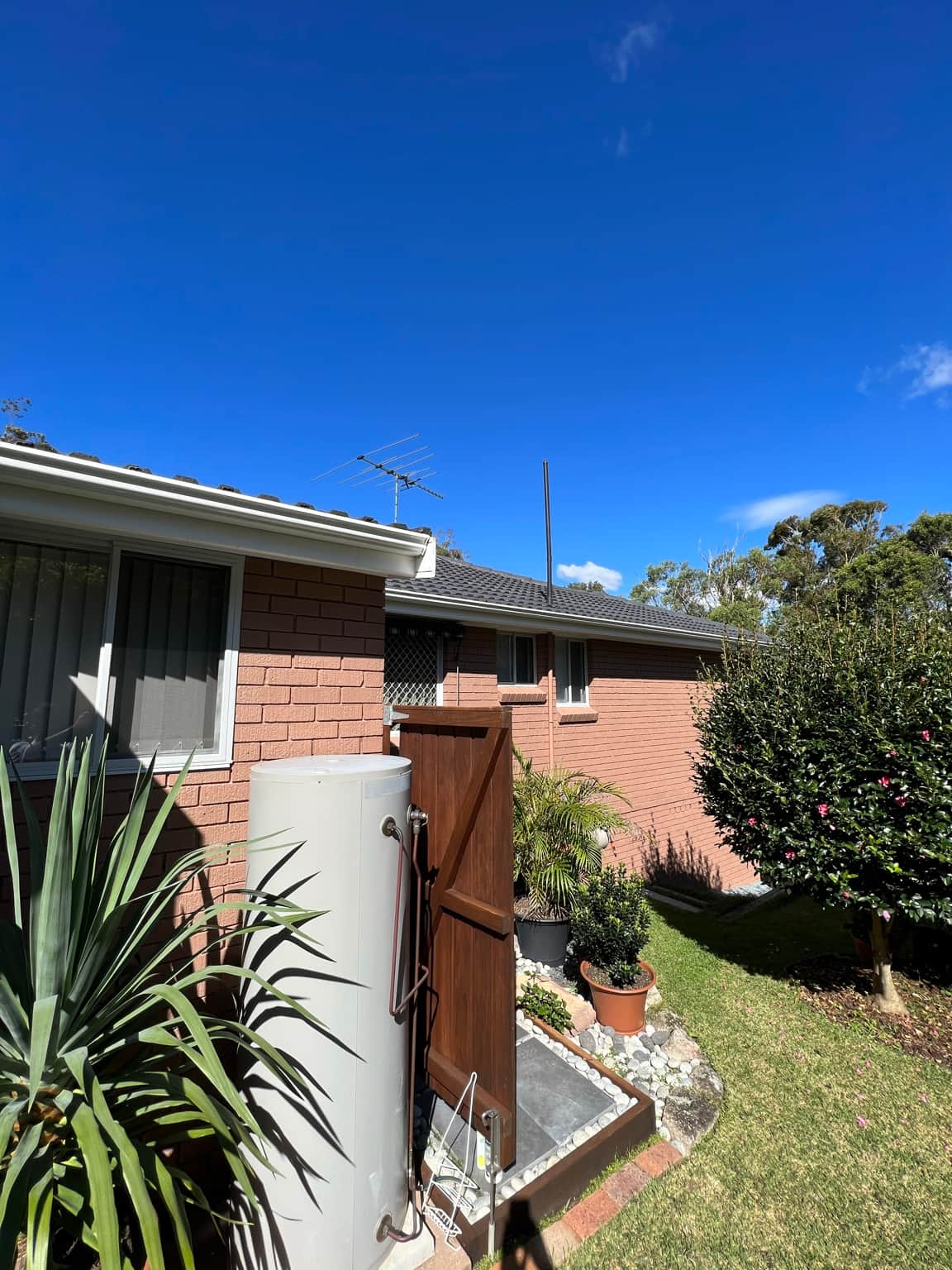 Completed exterior brick painting beside the garden in Cowan
