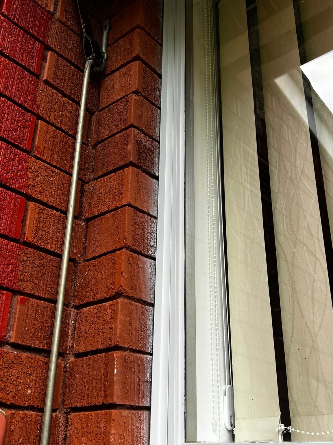 Close-up of an aluminium window frame beside red brickwork in Cowan