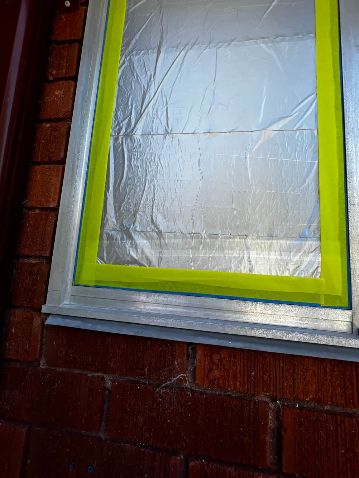 Masked aluminium window frame during the Cowan painting project