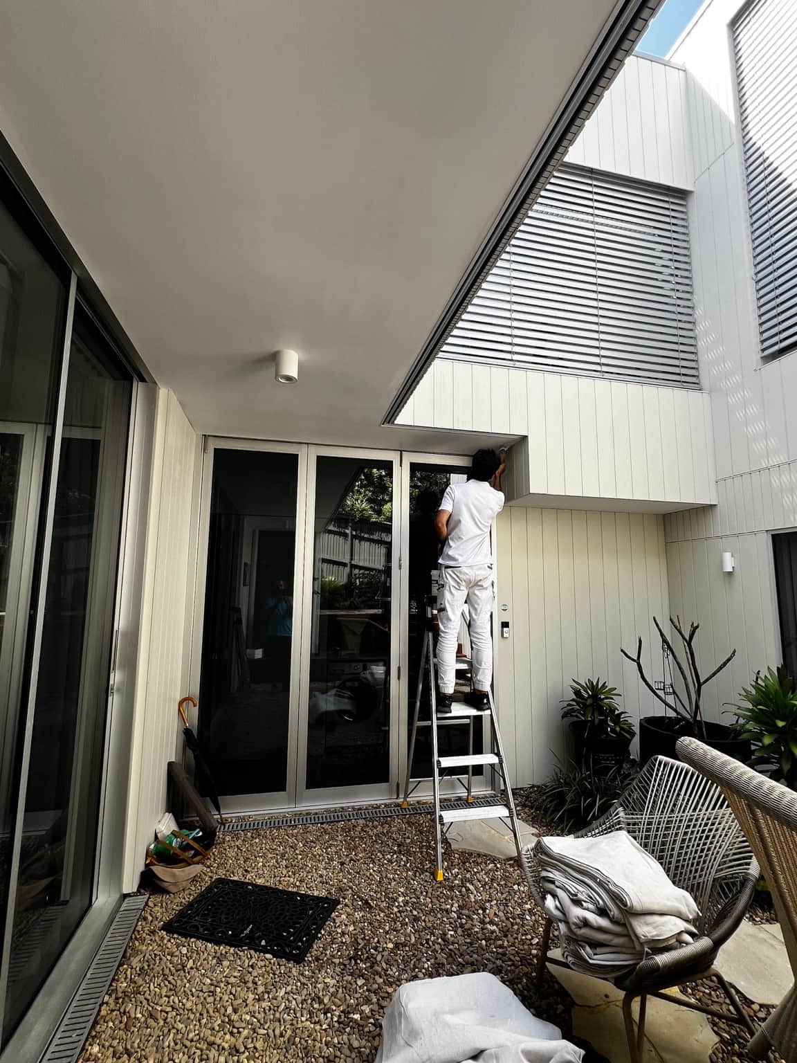Painter working from a ladder beneath the covered courtyard ceiling in Dover Heights