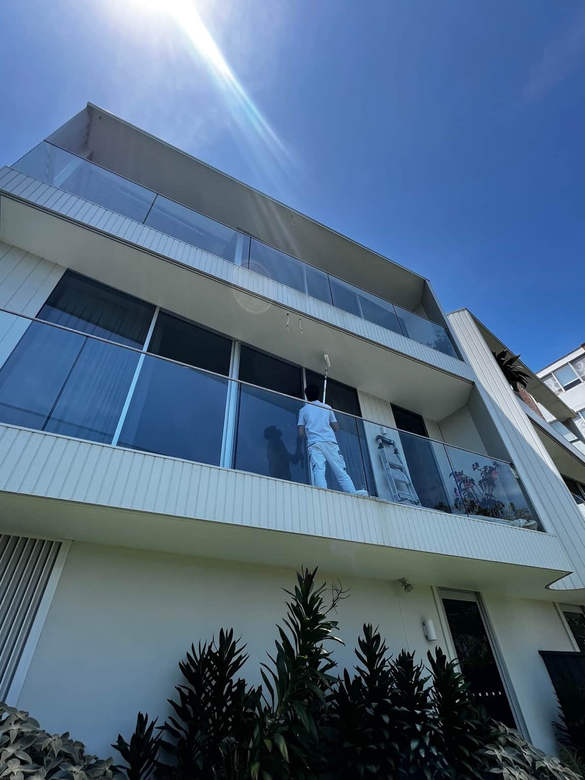 Alternate view of the light-coloured exterior and glass balcony at the Dover Heights painting project