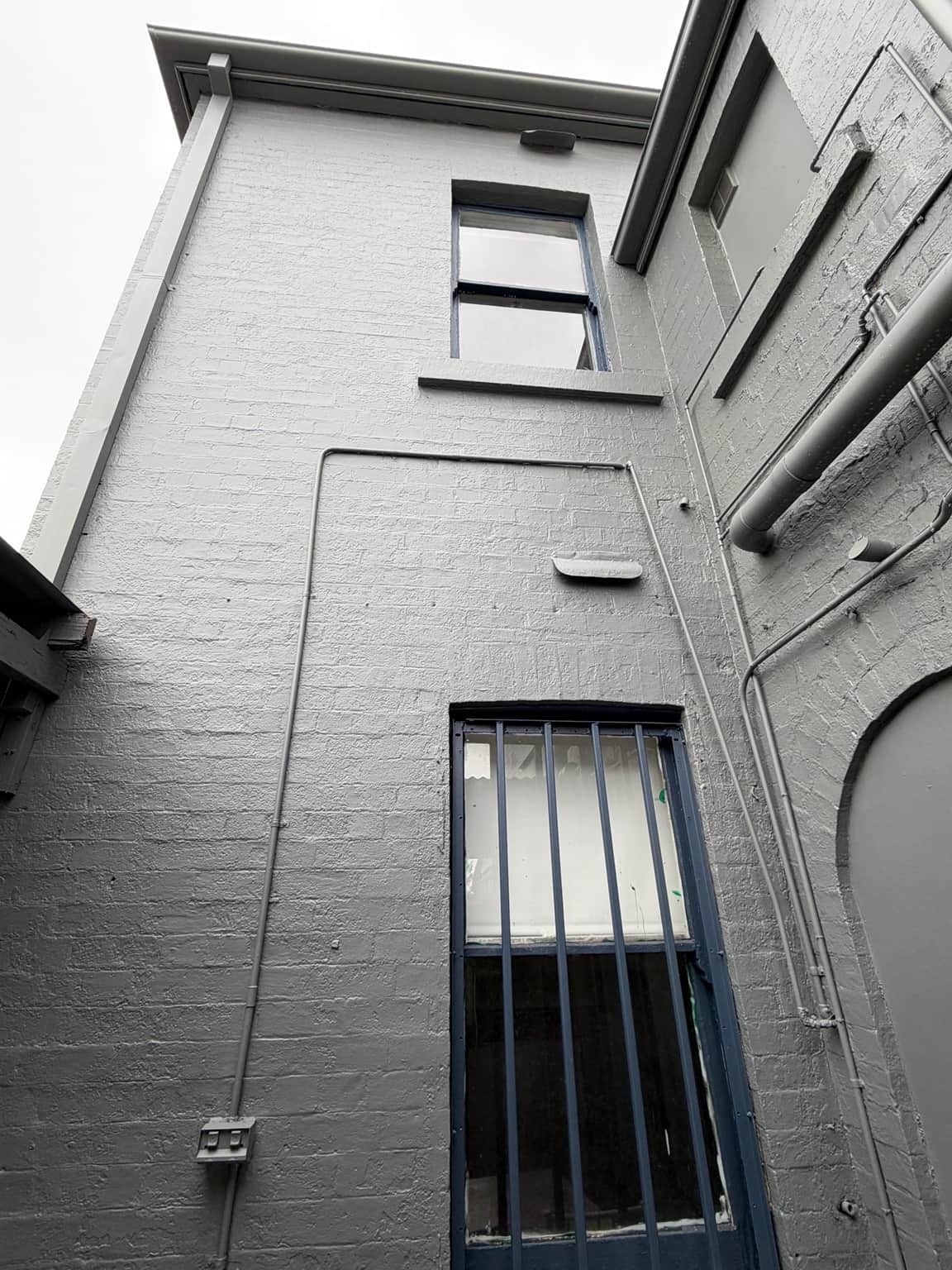 Rear masonry wall and window frames after exterior painting in Granville