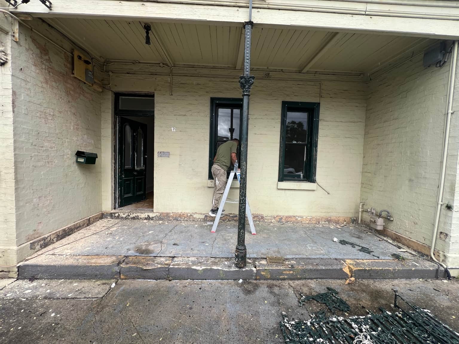 Yellow ground-floor verandah walls before exterior repainting in Granville