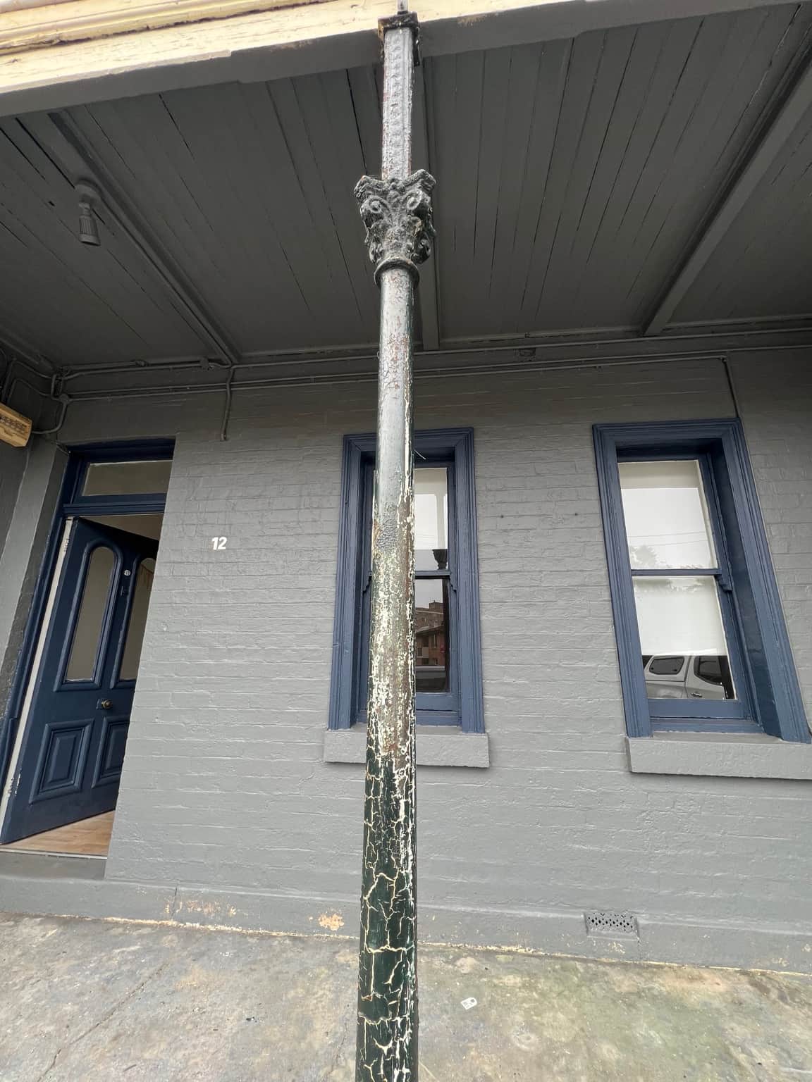 Grey verandah walls, window frames and decorative post during painting in Granville