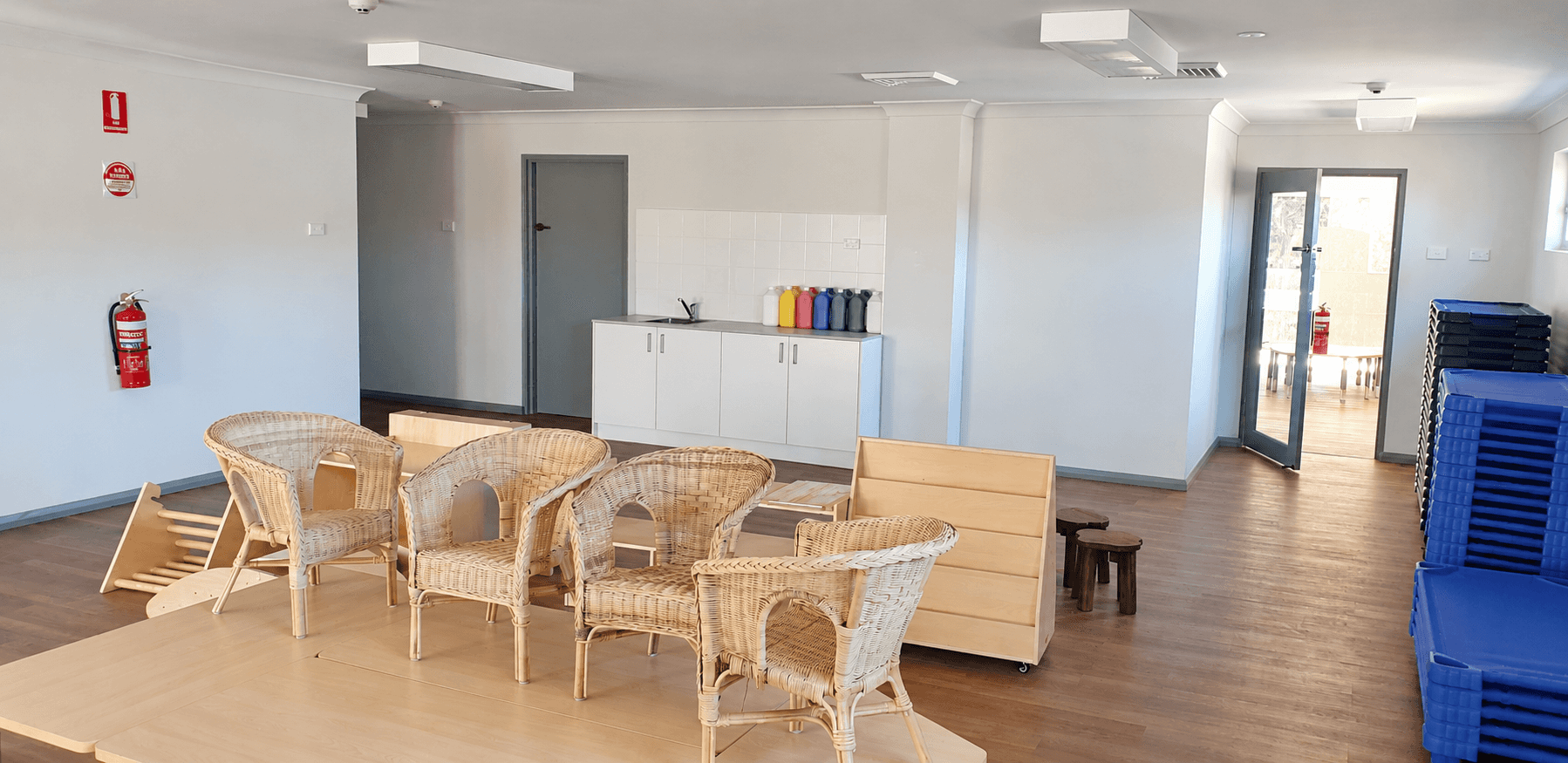 Painted childcare room with white walls, grey doors and stacked furniture in Hornsby