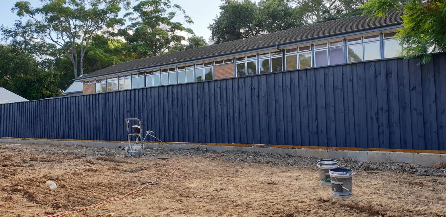 Wide view of the dark painted timber boundary fence in Hornsby