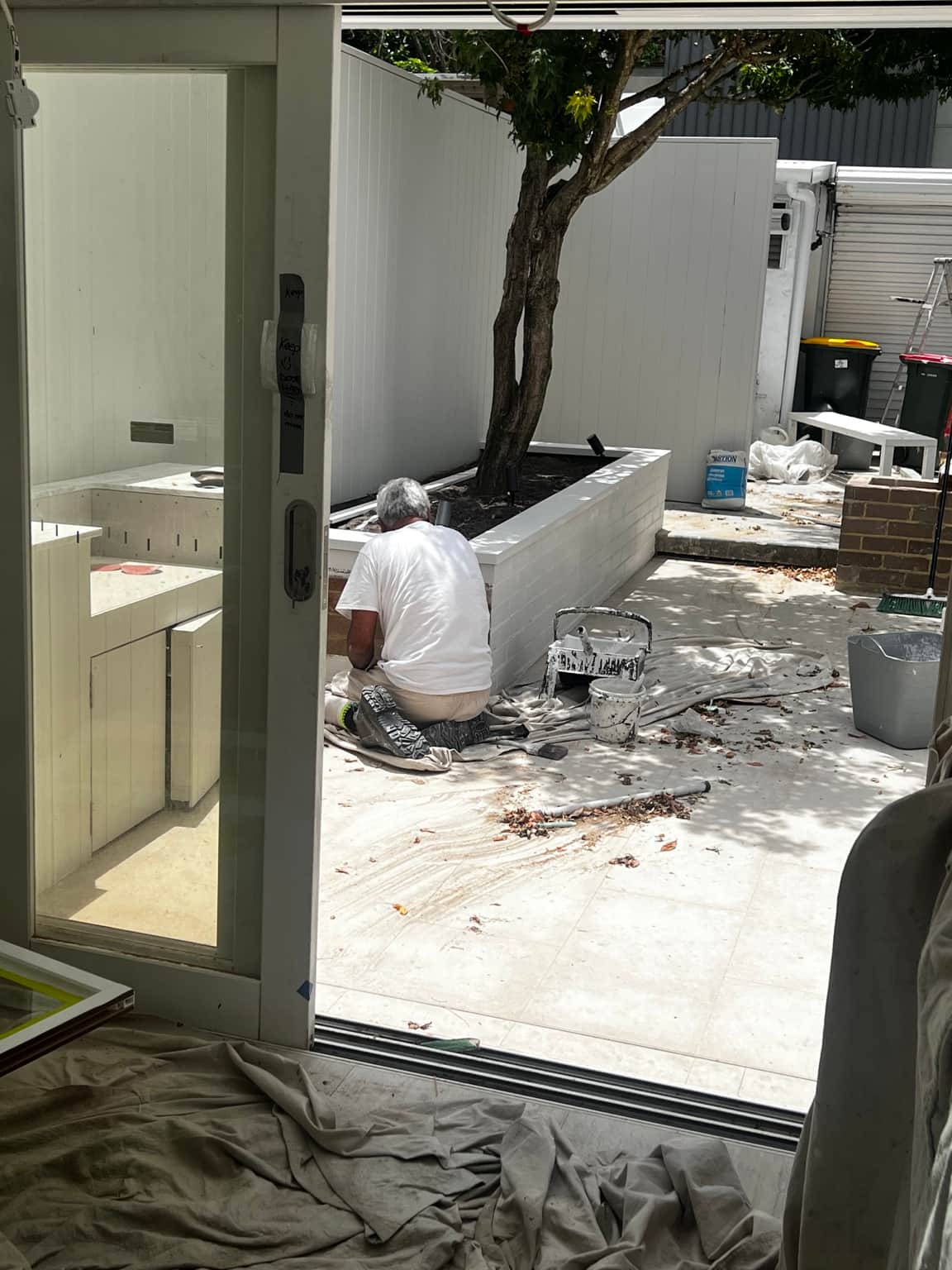 Painter working beside the courtyard planter during exterior painting in Newtown