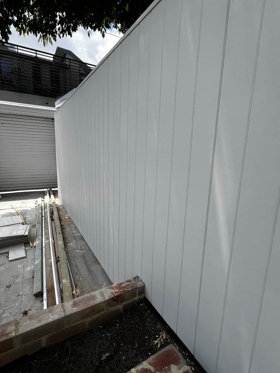 Close view of light-coloured vertical exterior cladding at the Newtown painting project
