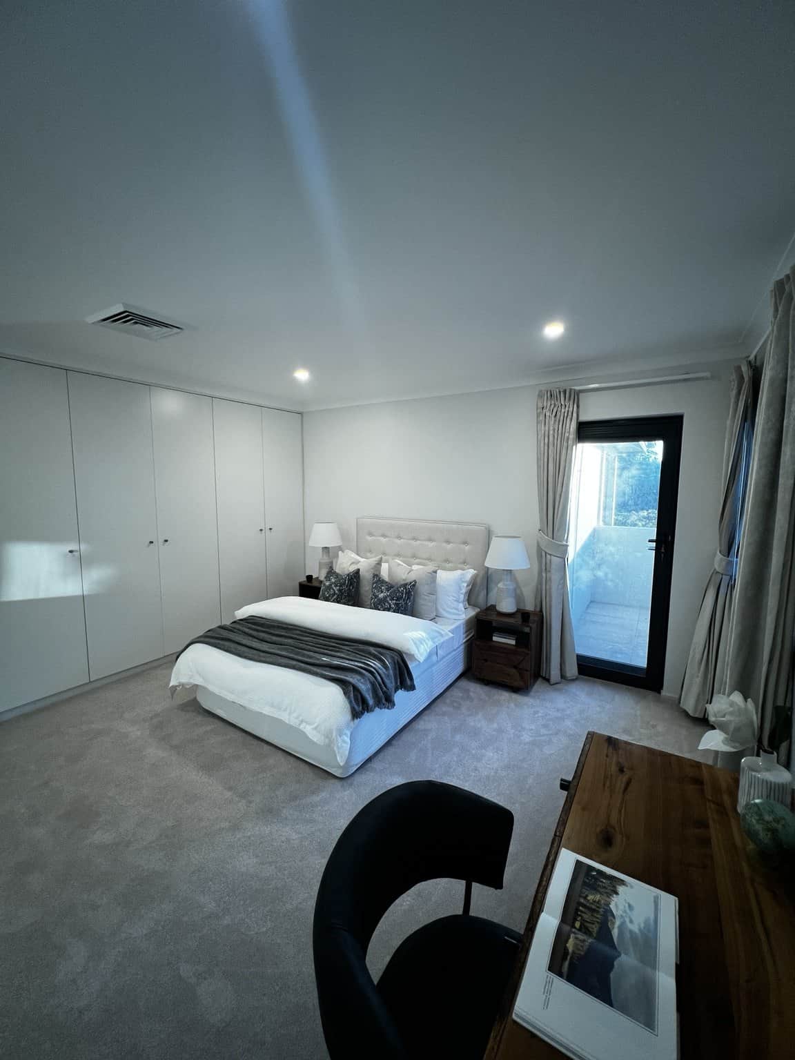 Northbridge bedroom with light painted walls and a glazed door beside the bed.