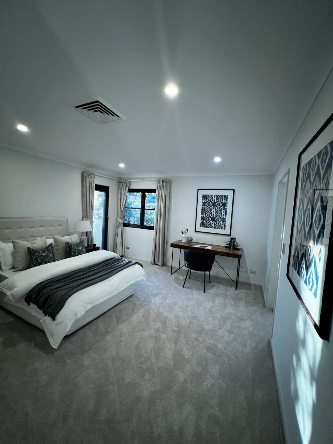 Light bedroom walls and ceiling beside a bed, desk and framed artwork in Northbridge.