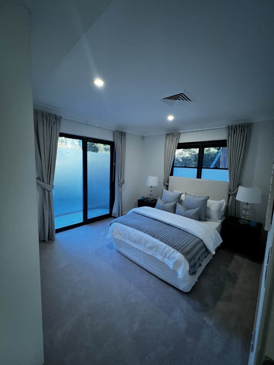 Northbridge bedroom with light walls, dark window frames and a sliding glass door.