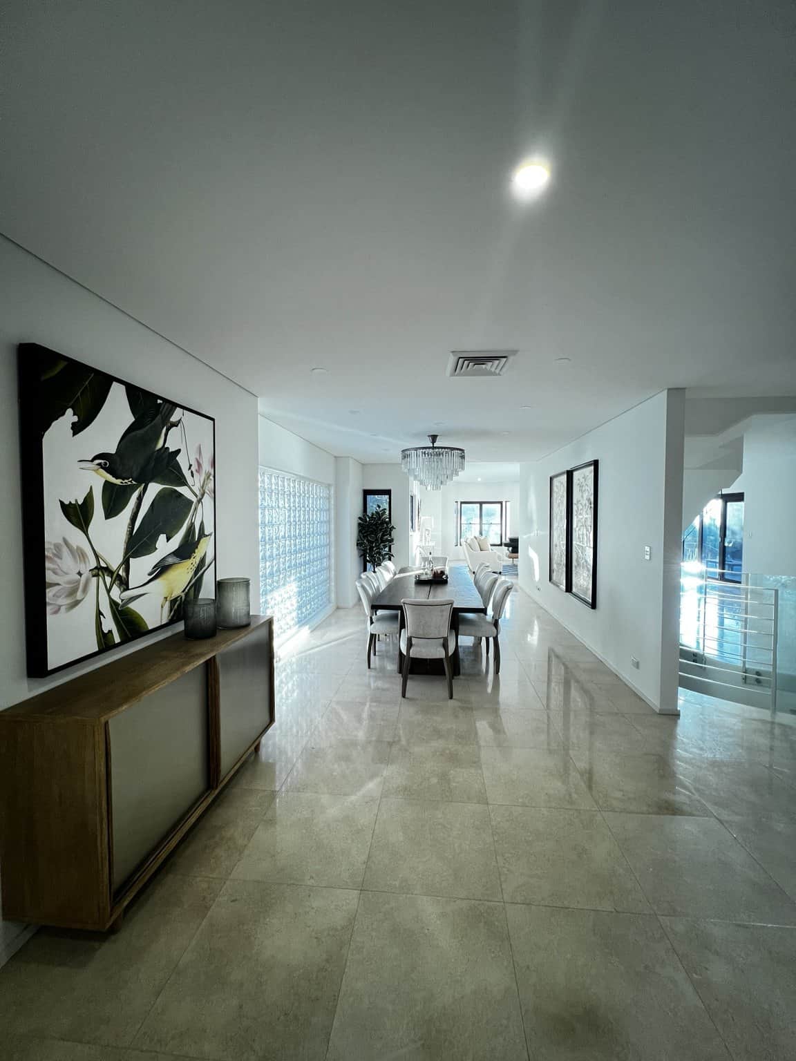 Northbridge dining room with light painted walls and ceiling, artwork and a long dining table.