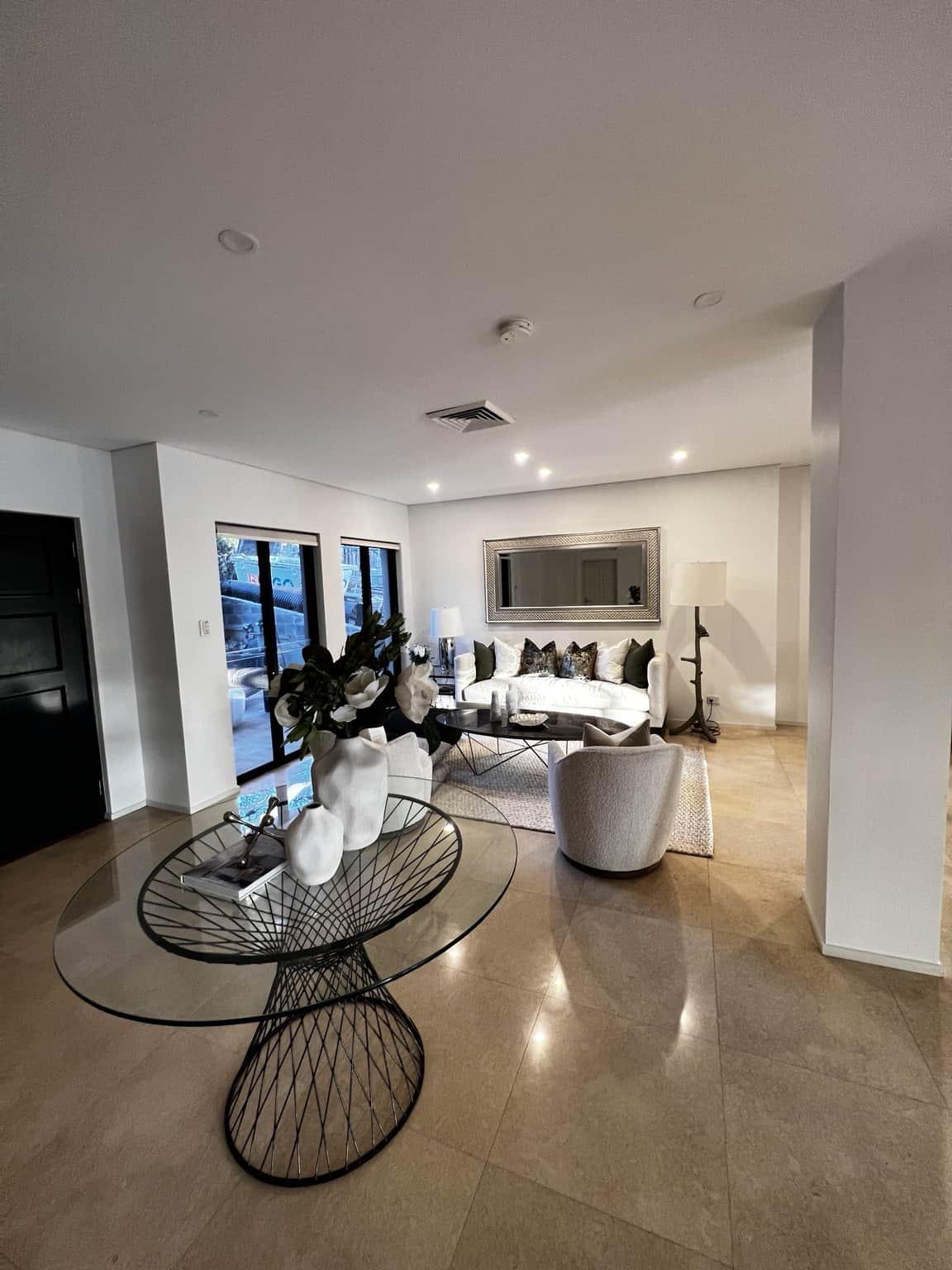 Northbridge entrance and lounge with light walls, a black door and a round glass console table.
