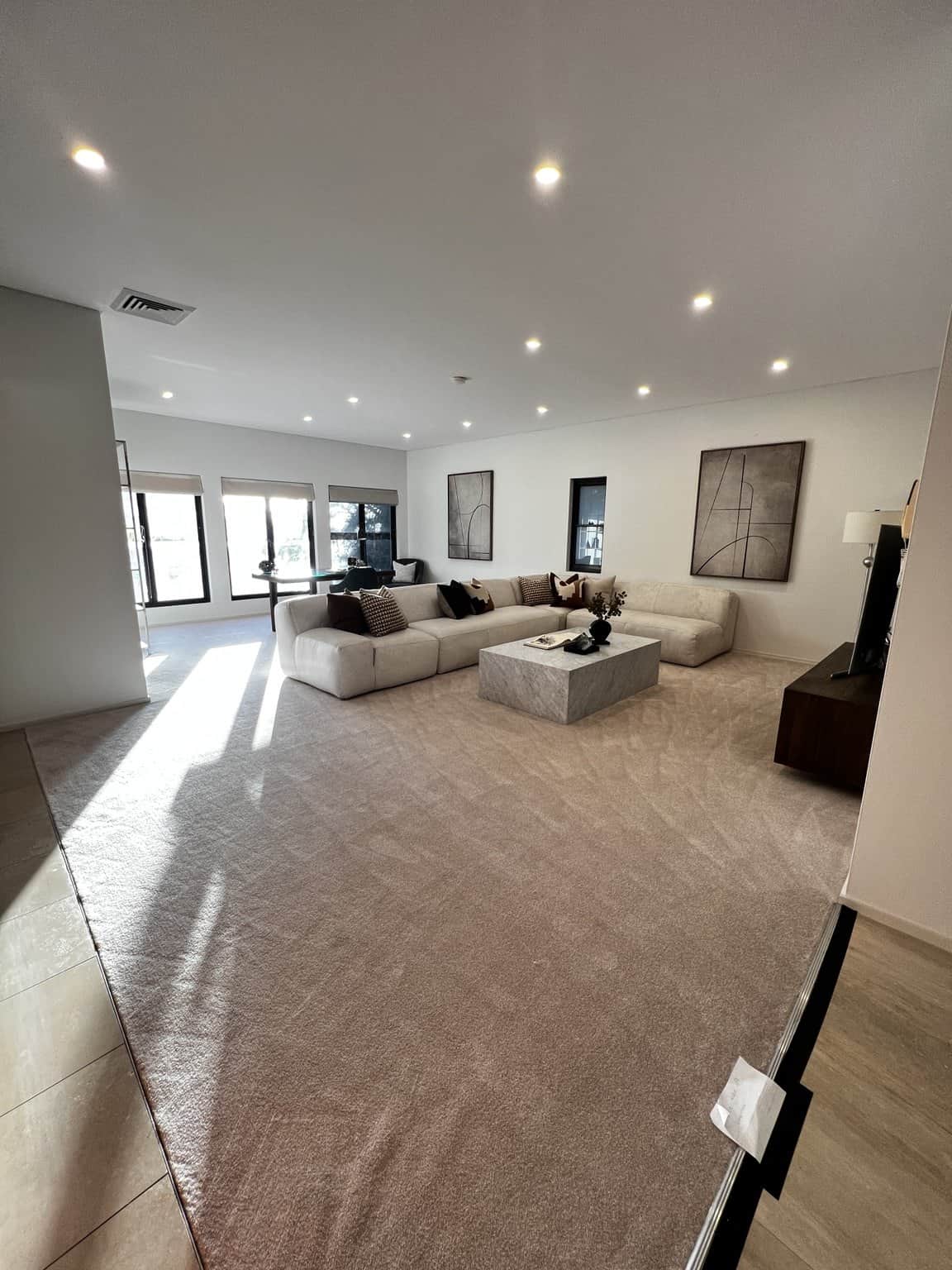 Northbridge family room with light painted walls and ceiling, cream seating and a stone coffee table.