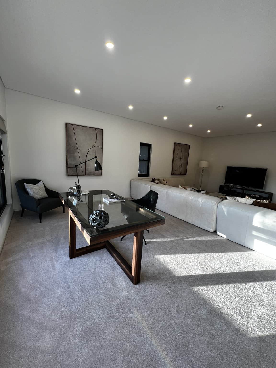 Northbridge home office and lounge with light painted walls, a glass desk and cream sofa.