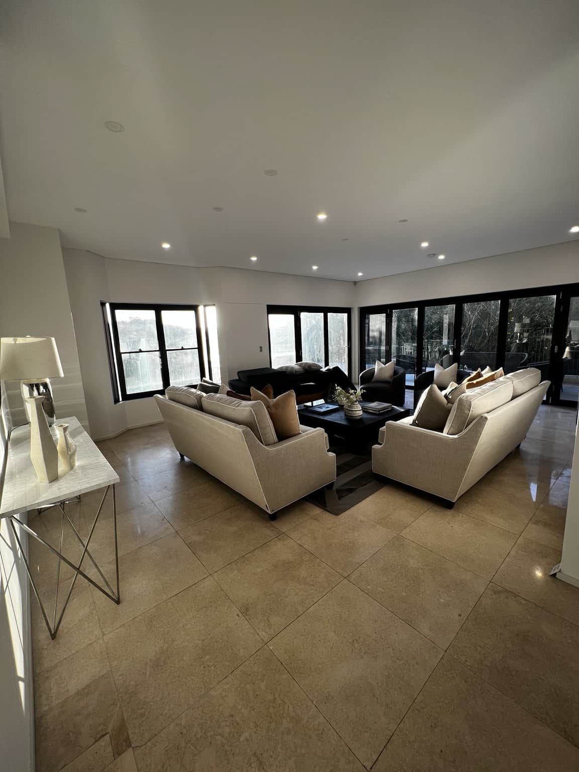 Northbridge living room with light painted walls, recessed ceiling lights and dark window frames.