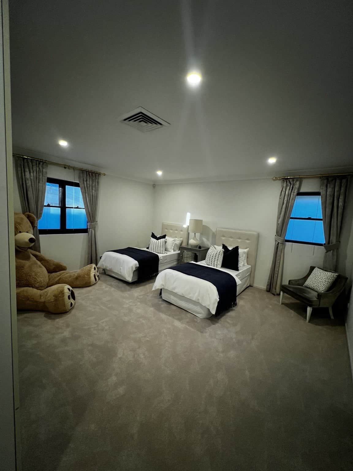 Northbridge twin bedroom with light walls, recessed ceiling lights and two beds.