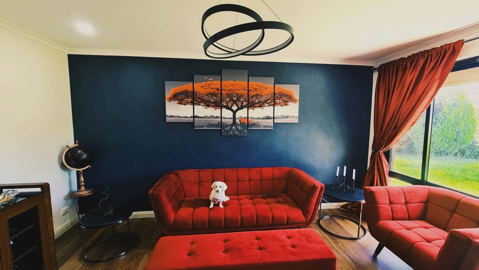 Completed deep blue French Wash feature wall with red seating and orange tree artwork in a St Clair living room
