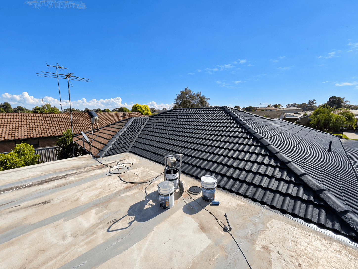 Wide roof-level view of the dark roof coating during the St Clair painting project