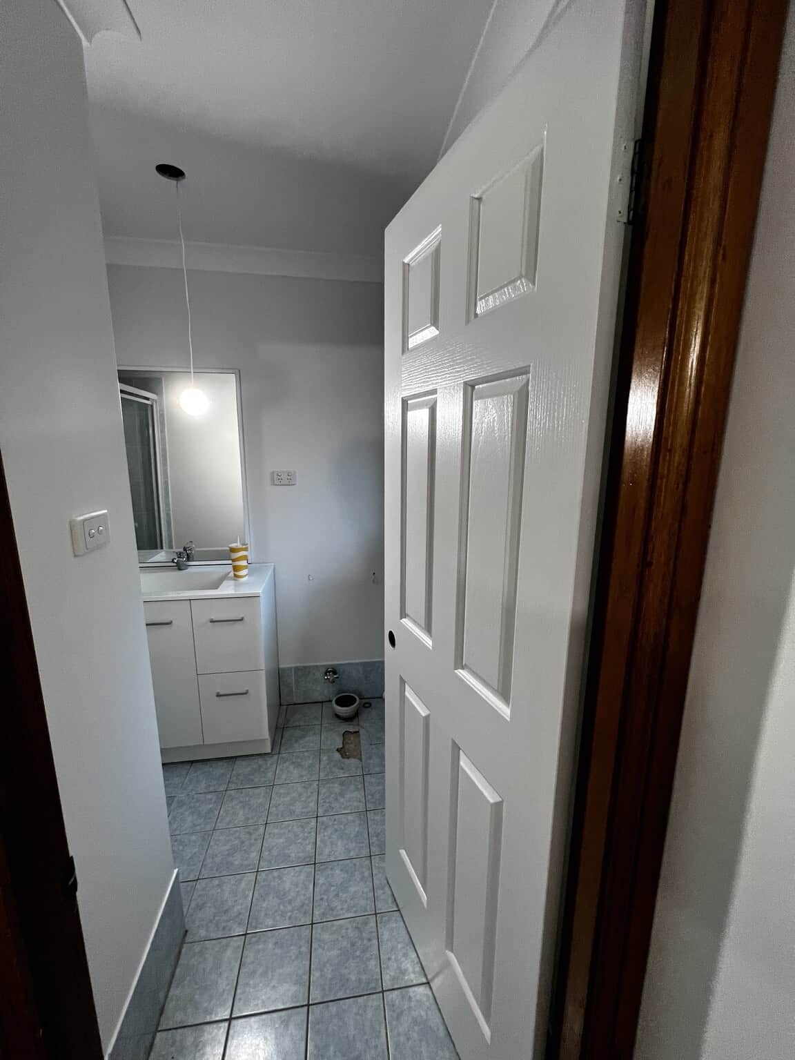 Freshly painted bathroom doorway with a white panelled door and vanity visible inside.