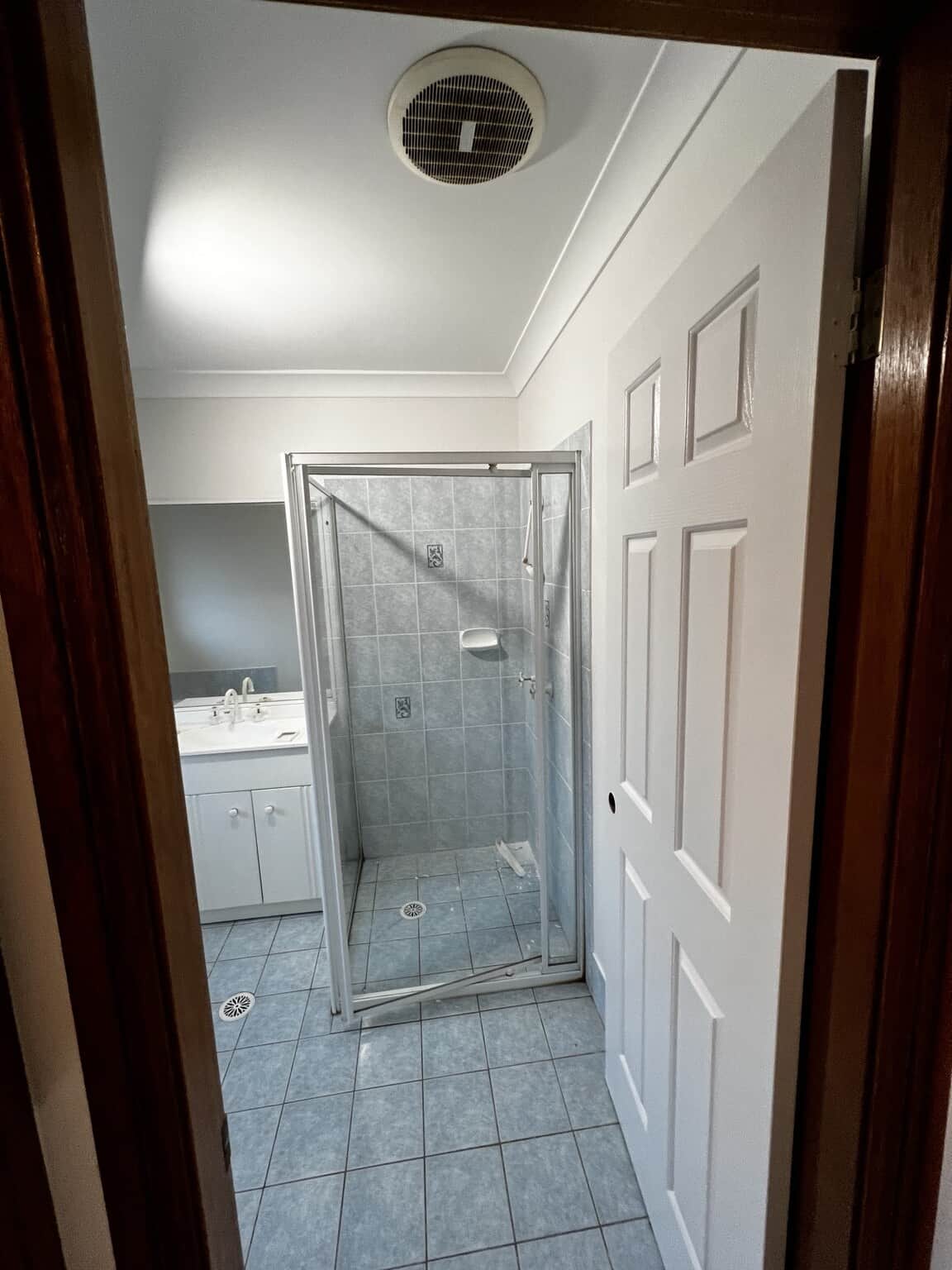 Bathroom entrance after repainting, showing a white panelled door beside the tiled shower.