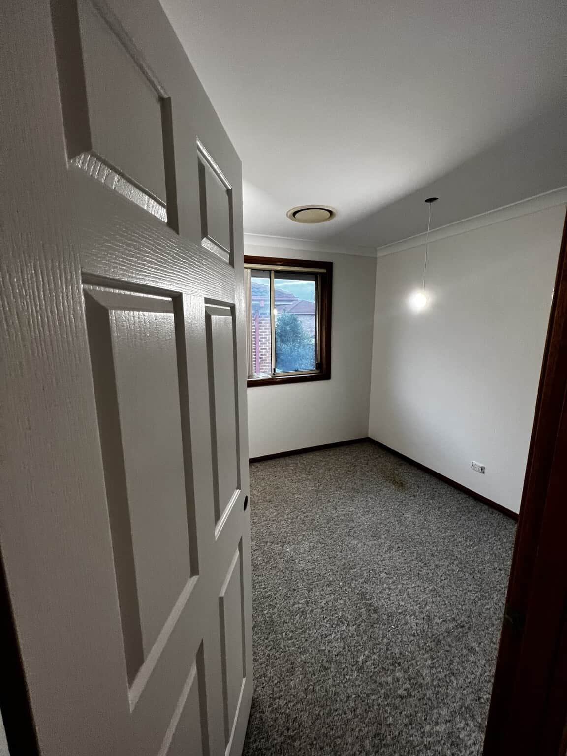View through a freshly painted bedroom door to Natural White walls and a timber-framed window.