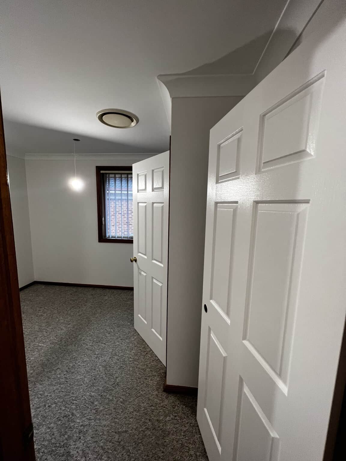 Bedroom entrance after repainting, showing Natural White Quarter doors against dark timber frames.