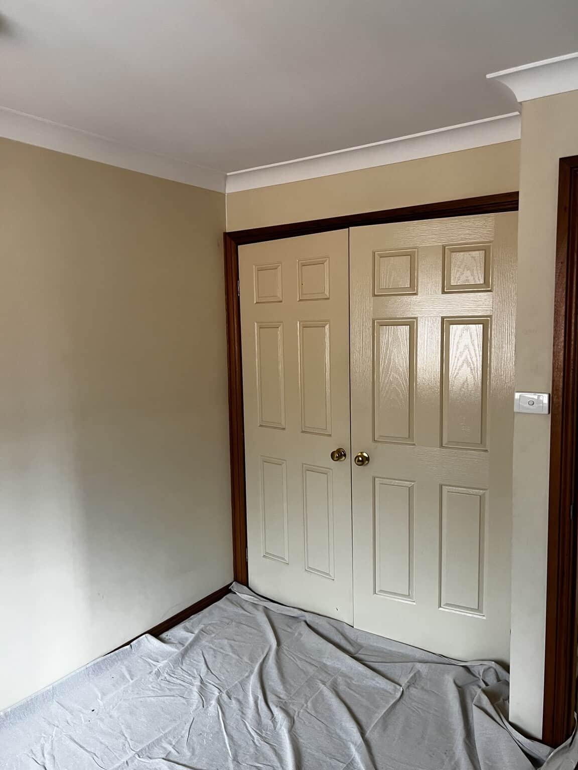 Double wardrobe doors and adjoining beige bedroom walls before the St Marys repaint.