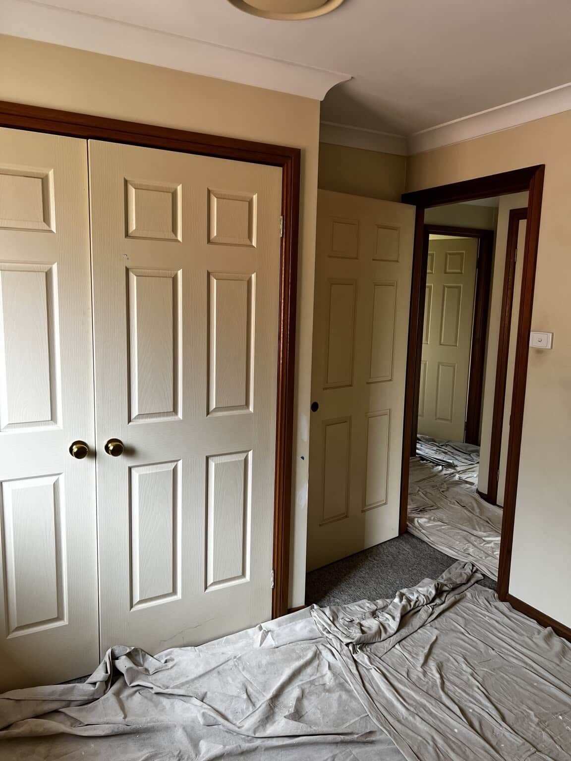 Cream bedroom and wardrobe doors with dark timber frames before repainting.