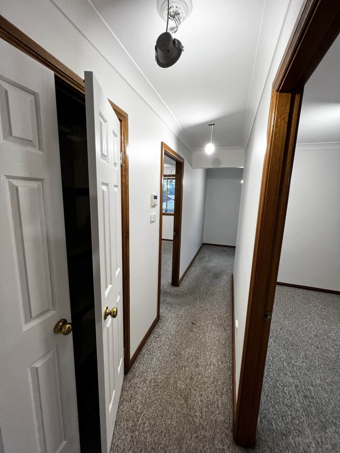 Hallway with Dulux Natural White walls and freshly painted doors alongside timber frames.