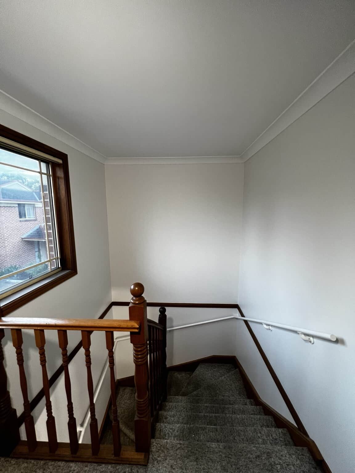 Stairwell with Dulux Natural White walls beside the existing timber balustrade and carpeted stairs