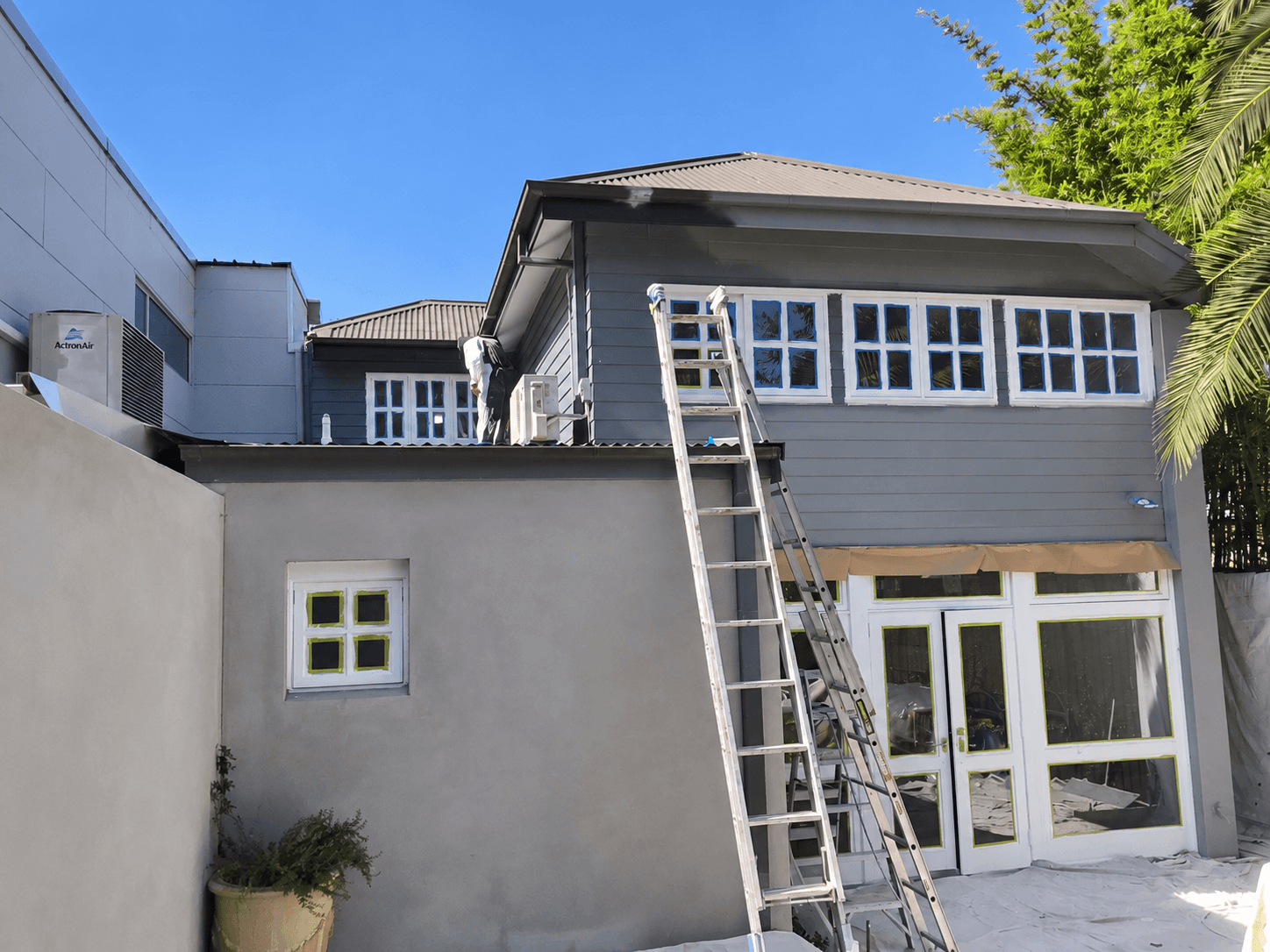 Rear exterior painting in progress with masked windows and access ladder in Stanmore