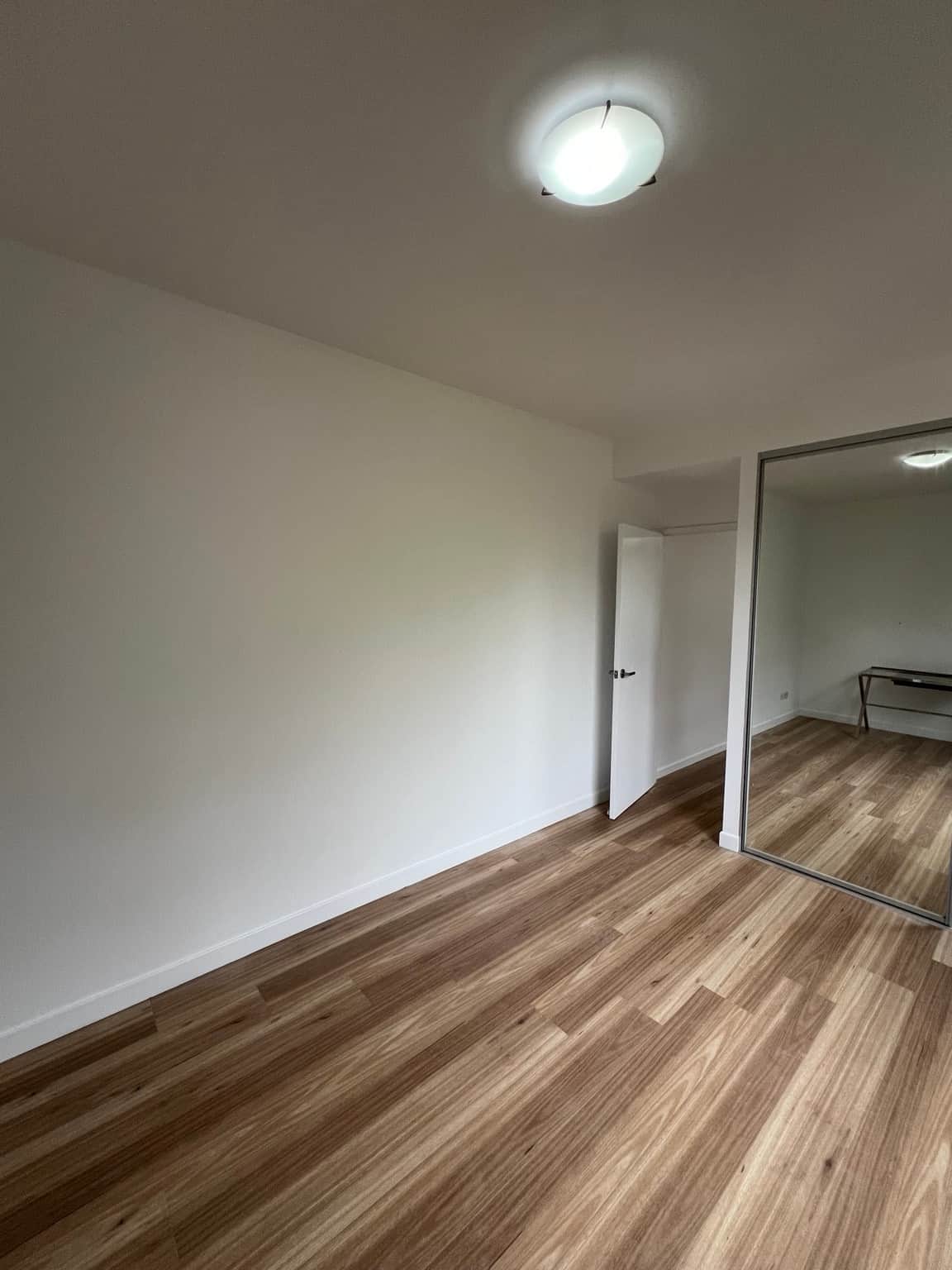 Finished Wahroonga bedroom with white walls, a painted door and mirrored wardrobe
