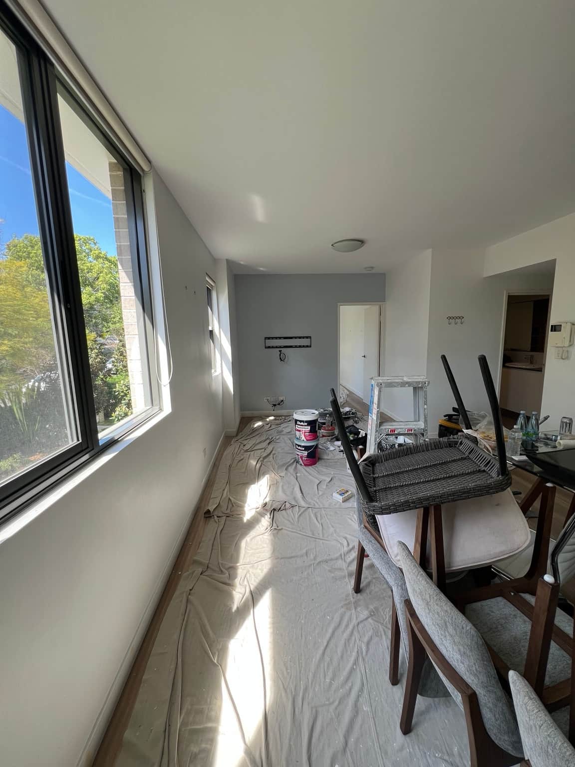 Wahroonga apartment living room before finishing, with a grey TV wall and covered furniture