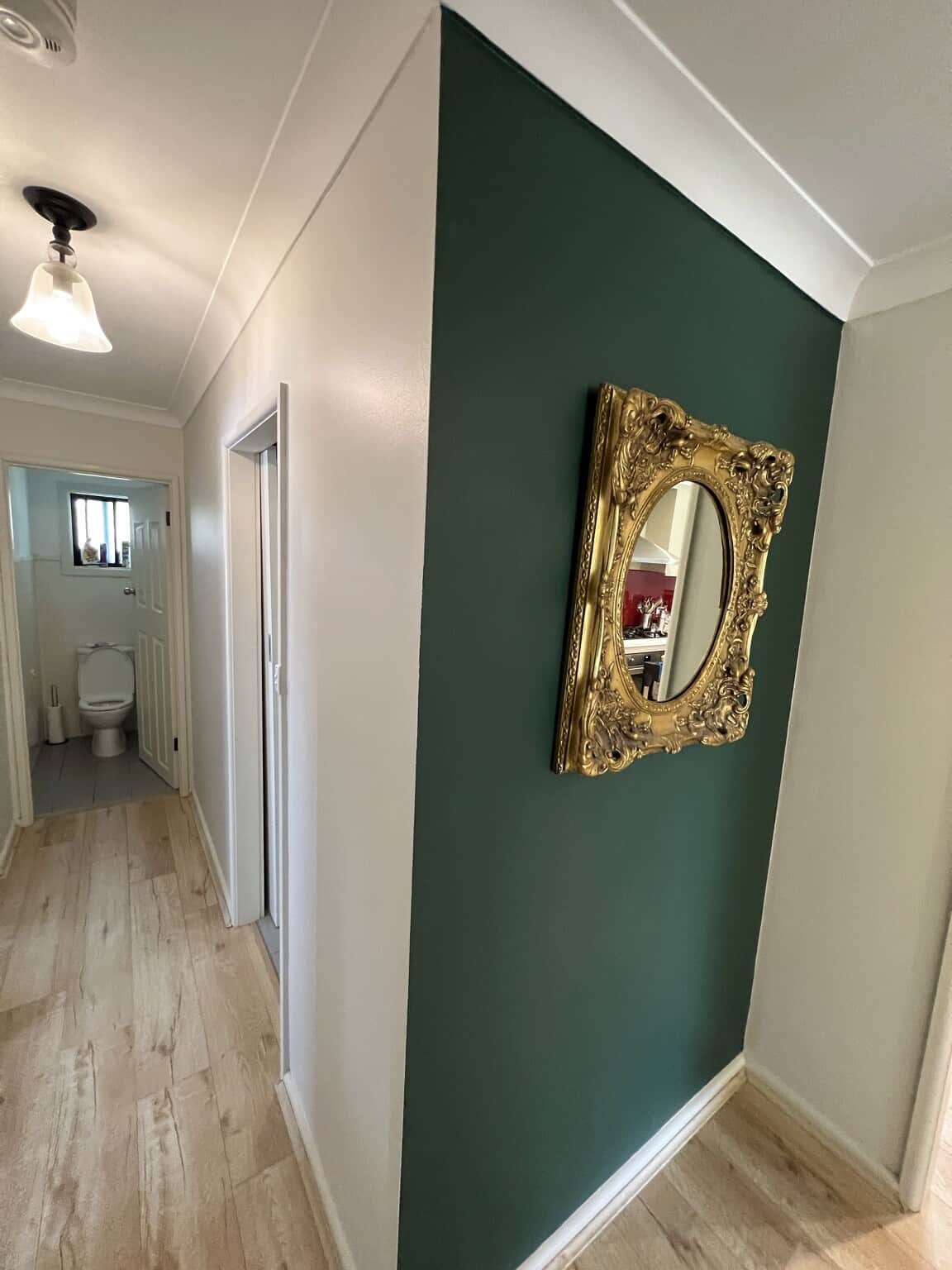 Deep green Taubmans Endure feature wall with a gold mirror in a freshly painted Winston Hills hallway.
