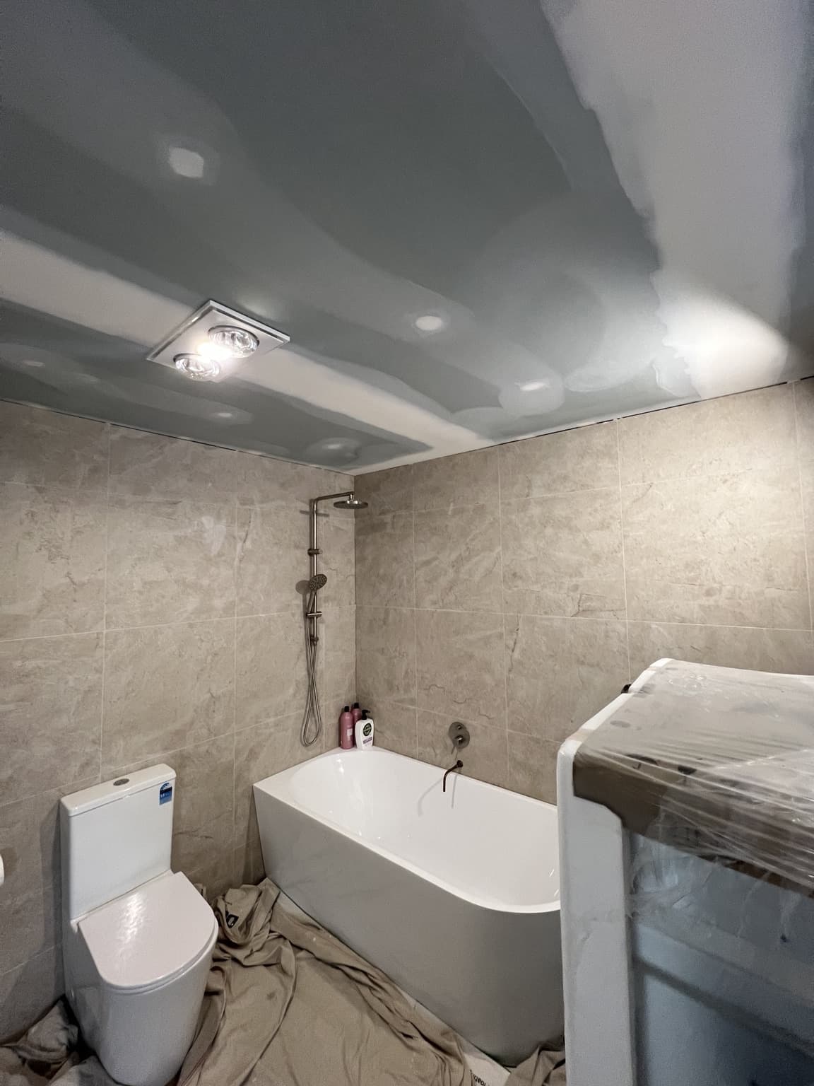 Finished painted bathroom ceiling above the bath and shower in Bexley, before