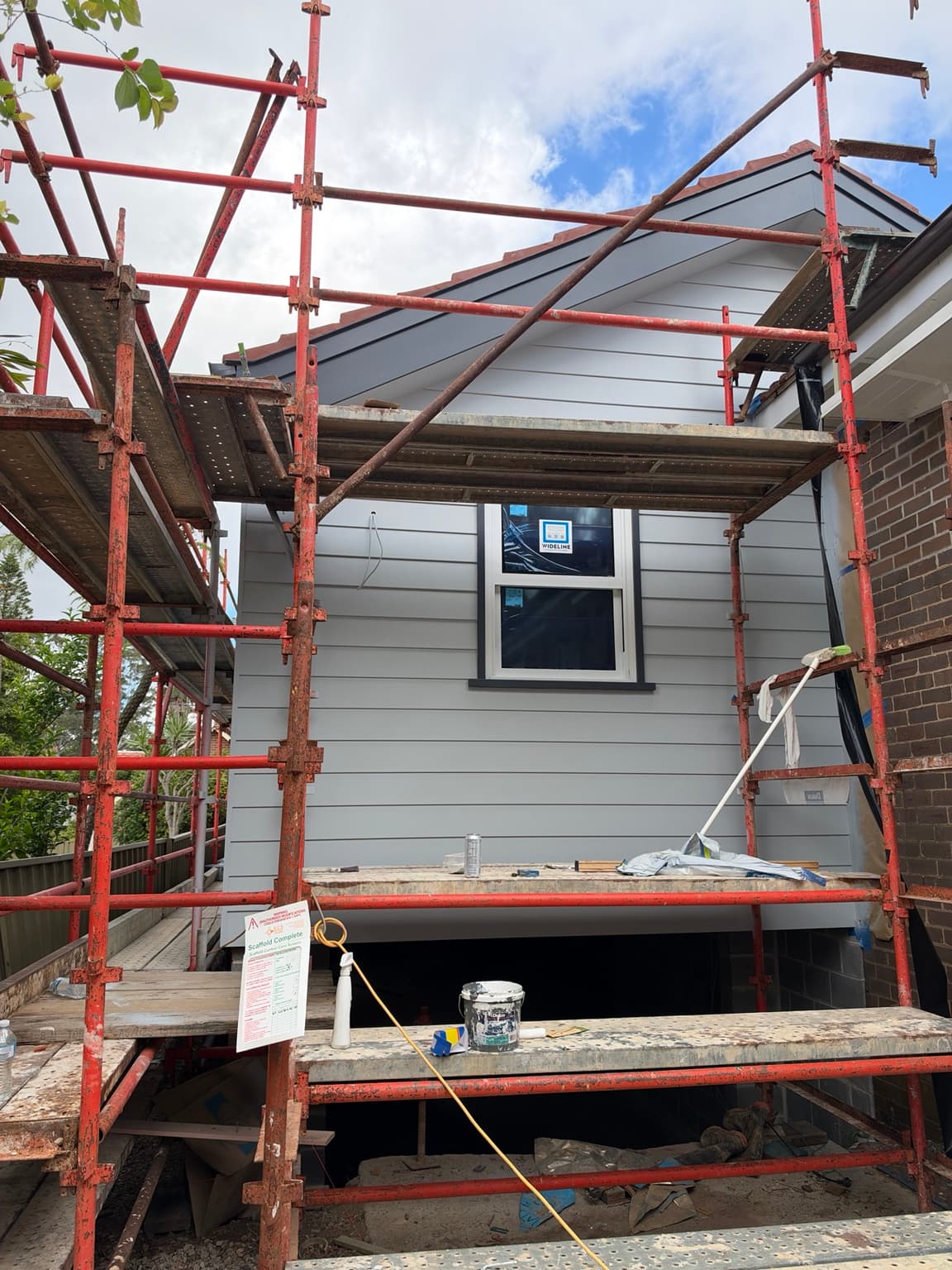 Light painted weatherboard gable with grey fascia and window trim in Beecroft, with scaffolding still in place, after